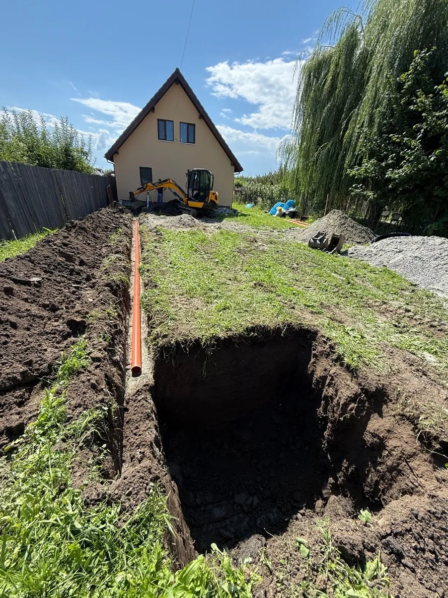 Săpătură pentru fosă septică și conductă în curte rezidențială